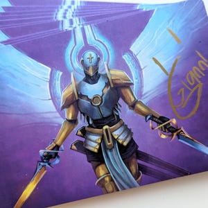 Puede incluir: Una pila de cartas con una ilustración digital de un guerrero futurista. El guerrero tiene un casco en forma de cruz, armadura dorada y dos espadas. El fondo es morado con detalles azules y blancos. Se ve una firma dorada.