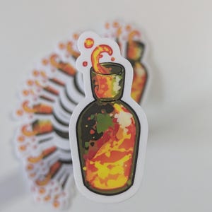 May include: A sticker of a glass bottle filled with a swirling orange and yellow liquid. The liquid is bubbling and overflowing from the bottle.