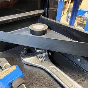 May include: A black plastic tool organizer tray with a black electrical tape roll inside. The tray is attached to the inside of a black toolbox. A blue wrench and a silver wrench are also visible in the image.