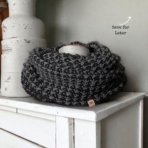 black and grey textured that looks like houndstooth crochet cowl sitting on a white dresser.
