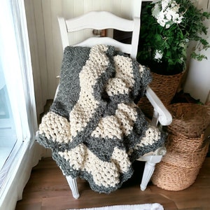a crocheted blanket sits on a chair beside a window