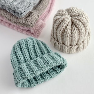2 crochet ribbed beanie hats one in soft aqua on in cream.