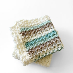 three crochet dishcloths made using the crochet crunch stitch clothes are in aqua cream and brown with a contrast border