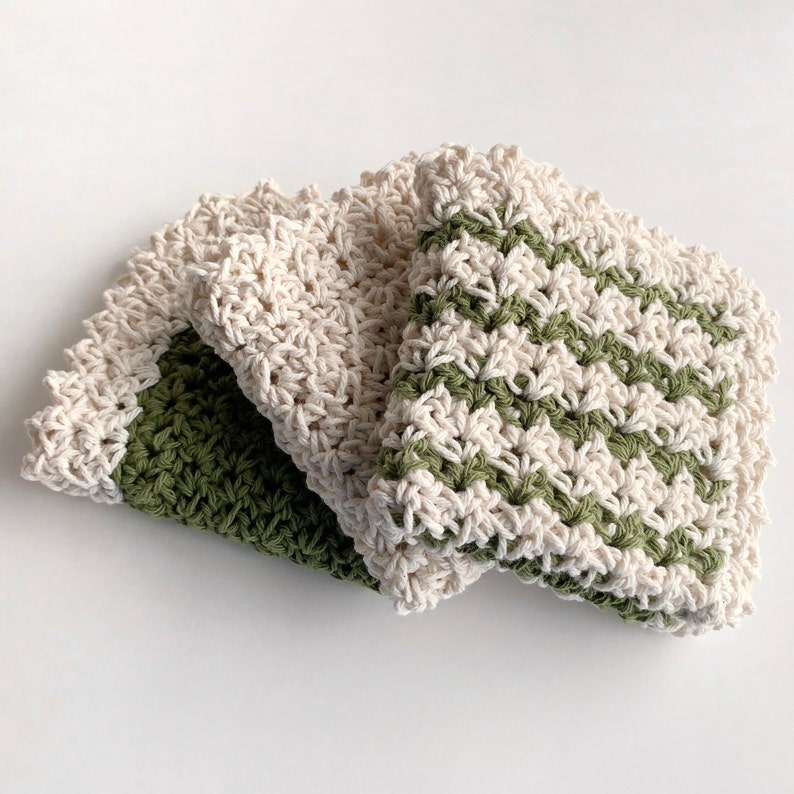 three crochet dishcloths that have a Lacey vintage farmhouse look cream, green with cream trim and green and cream striped with cream trim