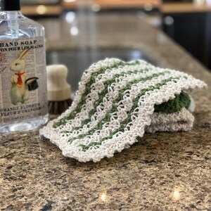 three crochet dishcloths that have a Lacey vintage farmhouse look cream, green with cream trim and green and cream striped with cream trim