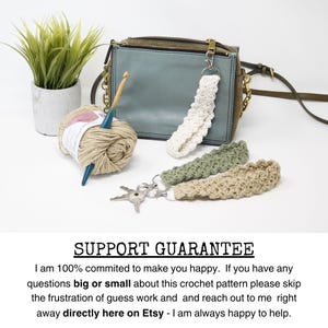 May include: A collection of handmade crochet keychains in white, green, and beige, displayed with a blue-green purse, yarn, and a crochet hook. The keychains are attached to silver key rings. A small potted plant is also in the image.