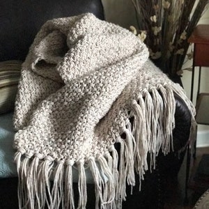 Beige crochet blanket with fringe that looks knit.  It is a throw size meaning it will cover legs and part of body not big enough for bed.  This is a crochet pattern not a finished item.