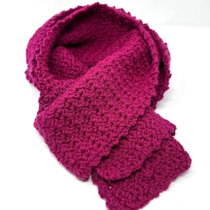 May include: A deep pink crocheted scarf with a scalloped edge.