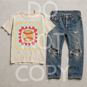 May include: A cream-colored t-shirt featuring a baseball graphic within a floral and geometric design, paired with distressed blue denim jeans. The jeans have ripped knees and a classic five-pocket design. The t-shirt has a vintage, worn look.