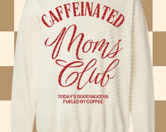 Op de afbeelding: Crèmekleurige sweatshirt met de rode tekst "CAFFEINATED Moms Club" in sierlijke letters. Daaronder staat "TODAY'S GOOD MOOD IS FUELED BY COFFEE". De trui heeft een ronde hals en lange mouwen.