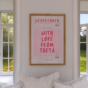 May include: A framed print with a pink guest check design. The text reads "GUEST CHECK" at the top, with "WITH LOVE FROM THETA" in the center. The frame is a light brown color.