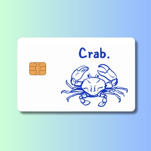 May include: A white card with a blue crab illustration and the word "Crab." The crab is drawn in a simple, cartoon style. An orange microchip is in the upper left corner.