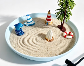 Jardín zen marino de escritorio con delfín, velero, faro, palmera y concha.