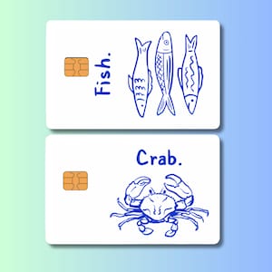 May include: Two white cards with blue illustrations and text. The top card says "Fish." and features three fish drawings. The bottom card says "Crab." and shows a crab drawing. Each card has a gold-colored chip.