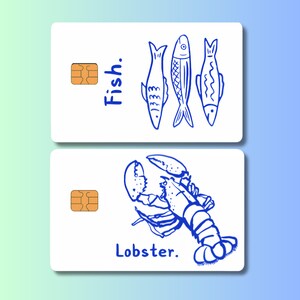 May include: Two white cards with blue illustrations. One card has three fish and the word "Fish." The other card features a lobster and the word "Lobster." Both cards have a gold-colored chip.