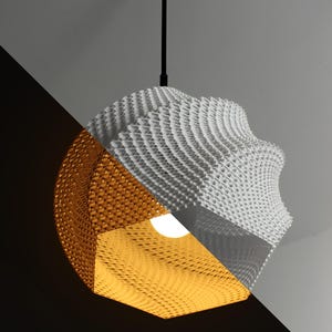 May include: A white and gold geometric pendant light fixture with a woven paper shade. The light is turned on and illuminates the room.