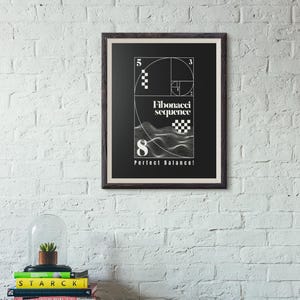 May include: A framed black and white art print displaying the Fibonacci sequence. The print features the numbers 3, 5, and 8, with the text "Fibonacci sequence" and "Perfect Balance!" The artwork is mounted on a white brick wall.