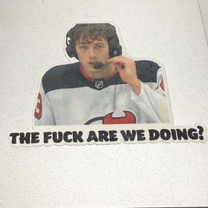May include: A sticker featuring a hockey player wearing a white and black jersey with the text "THE FUCK ARE WE DOING?" The player is wearing a headset with a microphone.