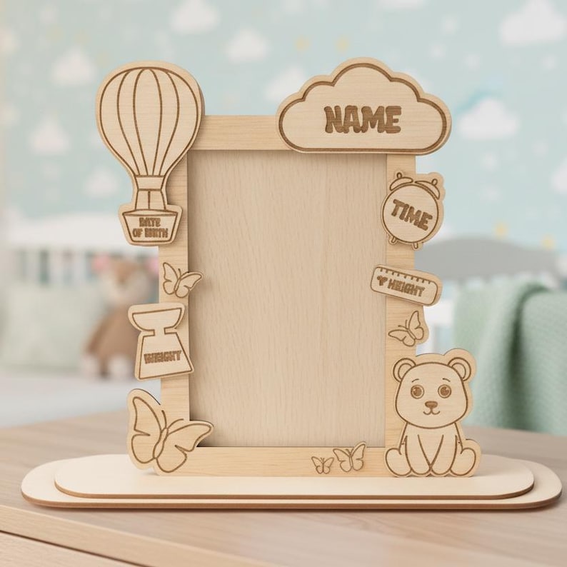 May include: Wooden baby photo frame with decorative cutouts of a hot air balloon, butterflies, a bear, and a cloud with the word "NAME". Includes cutouts for "DATE OF BIRTH", "WEIGHT", "TIME", and "HEIGHT".