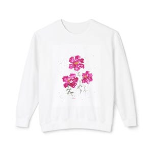 Puede incluir: Sudadera blanca con un diseño de acuarela de tres flores rosas en la parte delantera.