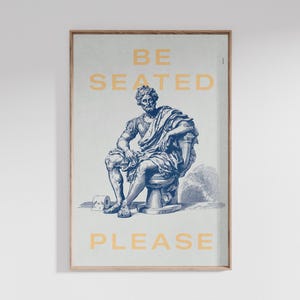 Könnte beinhalten: Gerahmter Kunstdruck mit einer blau-weißen Illustration einer klassischen Statue auf einer Toilette. Der gelbe Text lautet "BE SEATED PLEASE". Das Kunstwerk ist in einem hellbraunen Holzrahmen gerahmt.