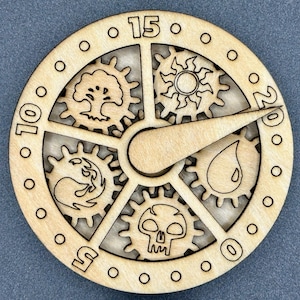 May include: A wooden spinner with five gears, each featuring a different Magic: The Gathering symbol. The symbols are: a tree, a sun, a drop of water, a flame, and a skull. The spinner has a wooden pointer and numbers 10, 15, and 20 around the edge.