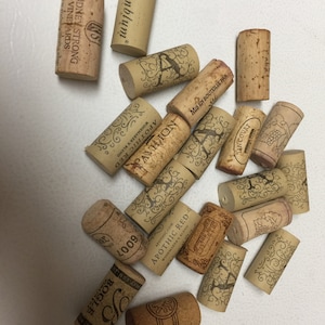 May include: A collection of 15 wine corks, some with brand names like "Rosenblum", "Rodney Strong", and "Apothic Red".