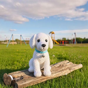 May include: A handmade white crochet puppy with black eyes and a black nose sits on a piece of wood. The puppy wears a light blue collar with a silver bell. The background is a green field with playground equipment.