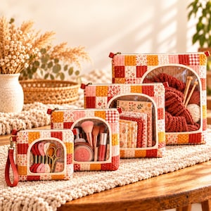 May include: A set of four quilted storage pouches in varying sizes, featuring a patchwork design of red, orange, and white floral and gingham patterns. Each pouch has a clear circular front window, a zipper closure, and a wrist strap.
