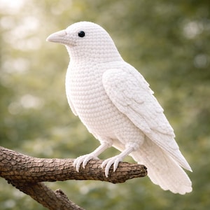 Puede incluir: Un pájaro blanco de ganchillo, posado en una rama marrón. El ave presenta una textura detallada, un pico y ojos negros. El fondo es un verde suave y borroso, sugiriendo un entorno al aire libre. Un objeto decorativo hecho a mano.