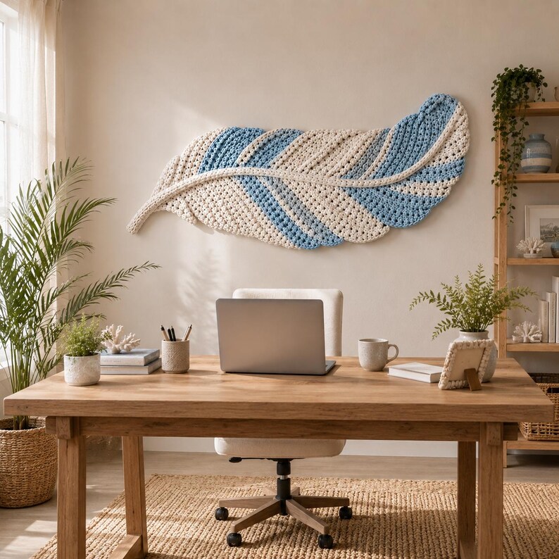 Pode incluir: Uma grande decora&ccedil;&atilde;o de parede horizontal em forma de pena, feita com fio grosso e texturizado em listras alternadas de creme e azul claro. A pe&ccedil;a apresenta uma nervura central e uma apar&ecirc;ncia tecida suave, montada numa parede lisa.