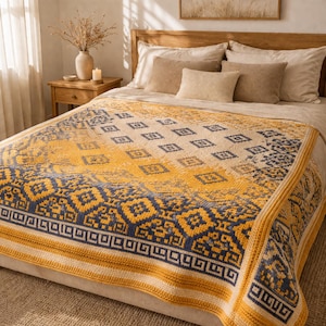 May include: A yellow and navy blue patterned blanket on a bed. The blanket features geometric designs and a border with a Greek key pattern. The bed has neutral-coloured pillows and a wooden headboard.