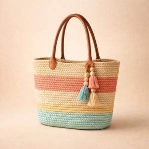May include: A woven tote bag with brown leather handles and colorful horizontal stripes in peach, yellow, and blue. The bag is adorned with tassels in matching colors and wooden beads.