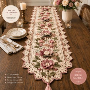 Könnte beinhalten: Cremefarbener Häkeltischläufer mit 3D-Blumendesign und elegantem Spitzensaum. Der Läufer zeigt rosa und grüne Blumen, eine Quaste und den Text "CROCHET TABLE RUNNER". Die Gesamtästhetik ist Cottagecore.