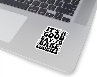 May include: A white sticker with black text that reads "It's a good day to bake cookies". The text is in a retro font style with stars around the words.