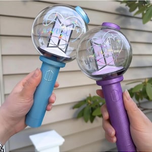 May include: Two light-up wands with clear globes and colored handles. The globes feature a logo and the word "you". One wand has a blue handle, the other purple. The wands are held up against a neutral background.