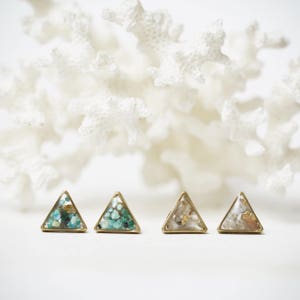 May include: Four gold triangle earrings with different colored resin inside. The earrings are on a white background.