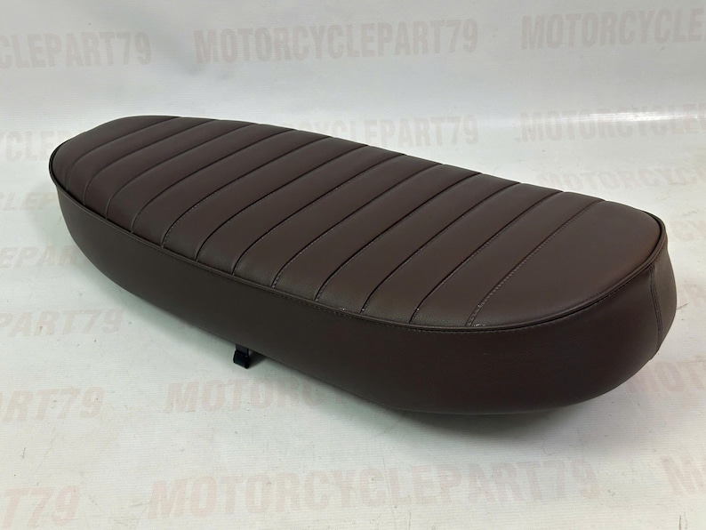 Peut inclure: Une selle de moto marron avec un design rembourr&eacute; et nervur&eacute;. Le si&egrave;ge est de forme ovale et semble &ecirc;tre fait de cuir ou d'un mat&eacute;riau similaire. La selle est de couleur marron fonc&eacute; et est con&ccedil;ue pour une moto.