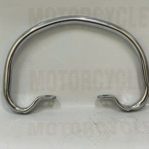 May include: A chrome-finished motorcycle part, likely a grab bar or handle. The curved bar has a smooth, reflective surface and features mounting points on each end. The part is designed for motorcycles.
