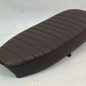 Peut inclure: Une selle de moto marron fonc&eacute; avec un design c&ocirc;tel&eacute;. La selle est de forme ovale et semble &ecirc;tre faite de cuir ou d'un mat&eacute;riau similaire. La selle est con&ccedil;ue pour un seul pilote.