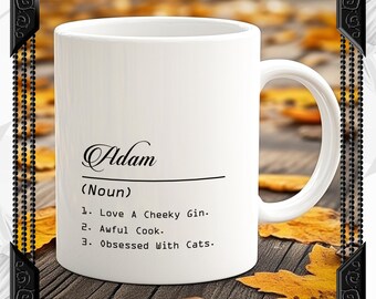 May include: White ceramic mug with a black design that says "Adam (Noun) 1. Love A Cheeky Gin. 2. Awful Cook. 3. Obsessed With Cats."