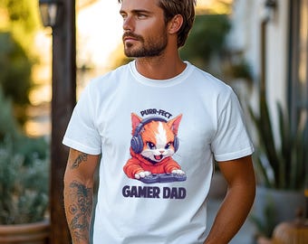 Op de afbeelding: Wit T-shirt met een cartoonkat die een koptelefoon draagt en een videogamecontroller vasthoudt. De tekst "purr-fect gamer dad" is op het T-shirt gedrukt.