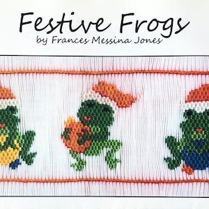 May include: Three green frogs wearing Santa hats are embroidered on a white fabric. The frog in the middle is holding a small orange pumpkin. The text "Festive Frogs by Frances Messina Jones" is above the frogs.