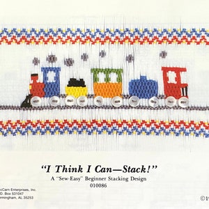 May include: A beginner stacking design featuring a colorful train with red, blue, green, and yellow cars. The design includes the text "I Think I Can-Stack!" and is bordered with red, blue, and yellow zigzags.