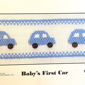 May include: A white and blue cross-stitch pattern featuring three blue cars with black wheels. The pattern is titled "Baby's First Car" and says "Easy to Stitch".