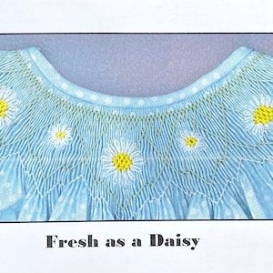 May include: A close-up of a light blue fabric with white polka dots and embroidered white daisies with yellow centers. The fabric is gathered and pleated, creating a ruffled effect. The text "Fresh as a Daisy" is printed below the fabric.