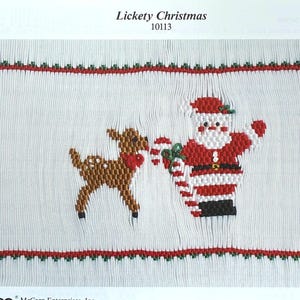 May include: A white fabric panel with a cross-stitch design featuring Santa Claus and a reindeer. Santa is in a red suit with a white beard, holding a candy cane. The reindeer has a red bow. The text "Lickety Christmas 10113" is at the top.