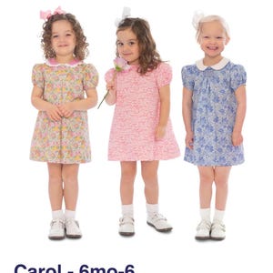 May include: Three young girls wearing floral print dresses with matching bows. The dresses are in shades of pink, yellow, and blue. Each dress has a Peter Pan collar and short sleeves. The girls are wearing white socks and shoes. The text "Carol - 6mo-6" is at the bottom.