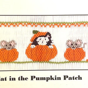 May include: A white fabric panel featuring a smocked embroidery design of a black and white cat wearing a pumpkin hat, flanked by two grey mice inside orange pumpkins. The text reads Cat in the Pumpkin Patch, COPYRIGHT USA, CROSSEYED CRICKET, 2015, Plate #373.