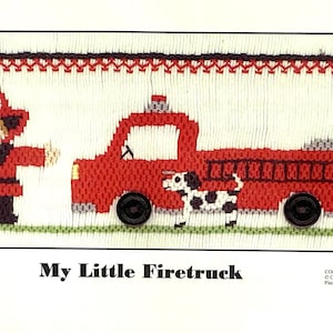 May include: A cross-stitch design featuring a red fire truck, a firefighter, and a Dalmatian dog. The firefighter wears a red hat with the number 1. The text "My Little Firetruck" is at the bottom.
